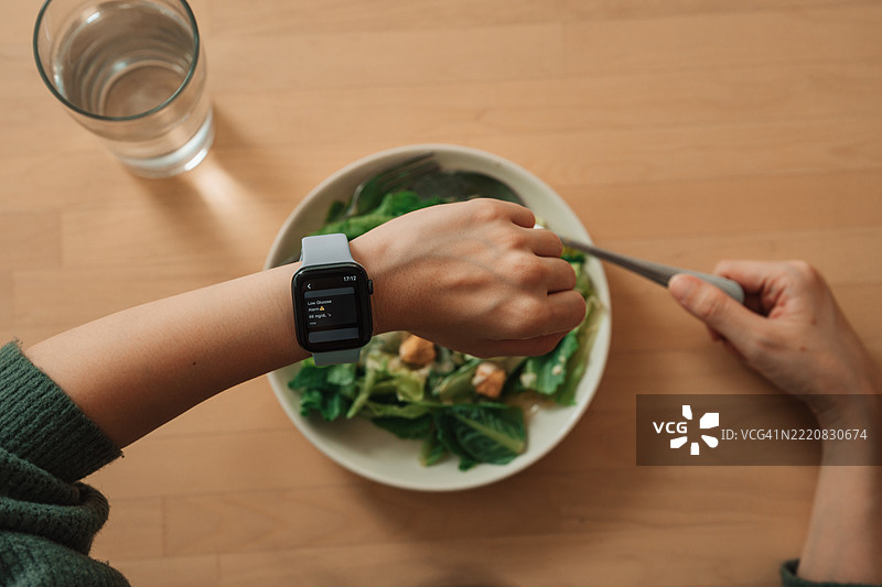 亚洲女性使用智能手表监测血糖水平，享受可穿戴技术带来的实时健康监测便利。图片素材