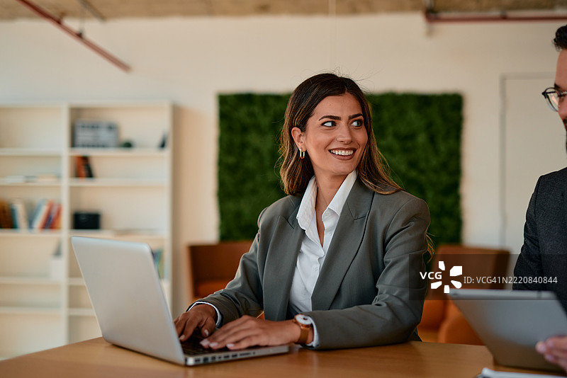 女商人在会议中一边打字一边看着她的同事图片素材