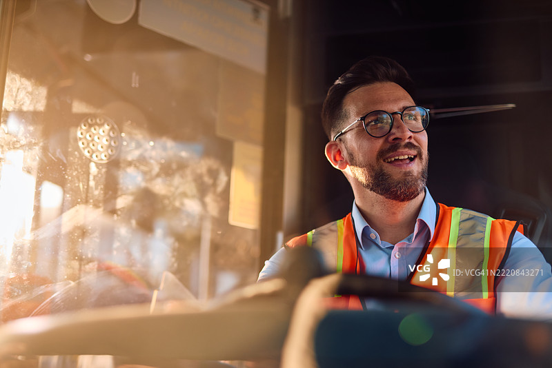 微笑的叉车司机穿着安全背心在仓库内驾驶图片素材