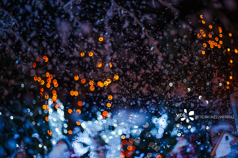 雪和圣诞灯光虚化的背景中有圣诞老人雕像图片素材