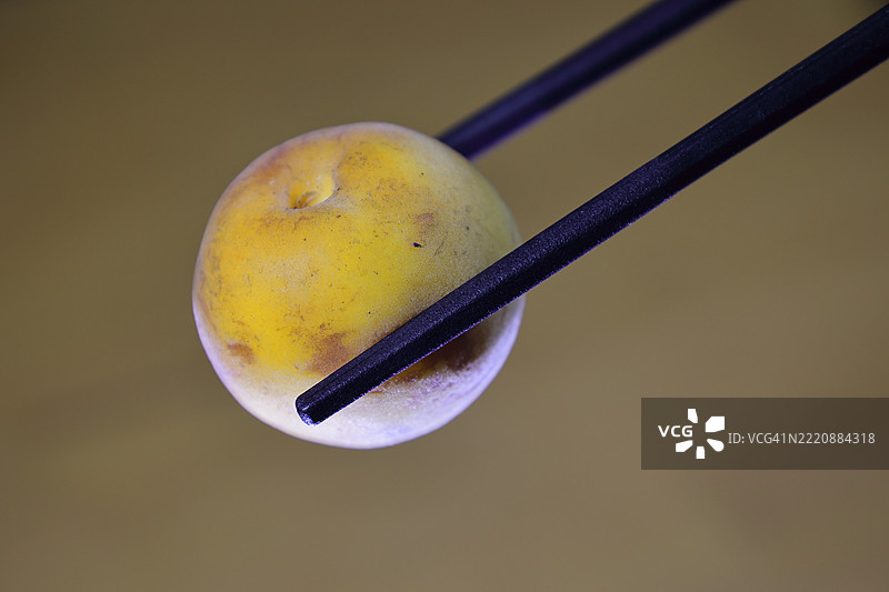 生色和皮肤受损的梅干放在筷子上图片素材