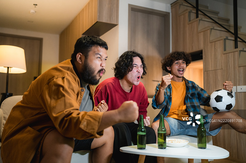 一群兴奋的足球迷在电视前欢呼庆祝，因为他们最喜欢的球队进球了图片素材