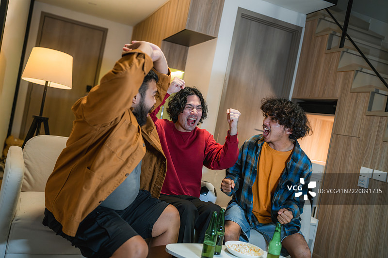 一群兴奋的足球迷在电视前欢呼庆祝，因为他们最喜欢的球队进球了图片素材