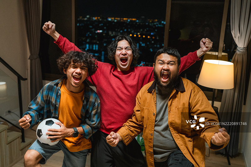 一群兴奋的足球迷在家中为比赛欢呼的肖像图片素材