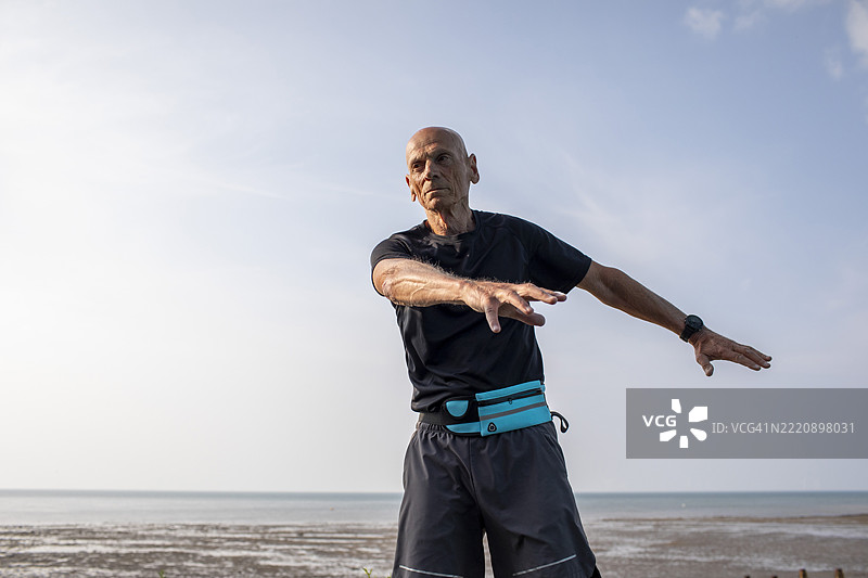 活跃的老年男性在海边做热身运动图片素材