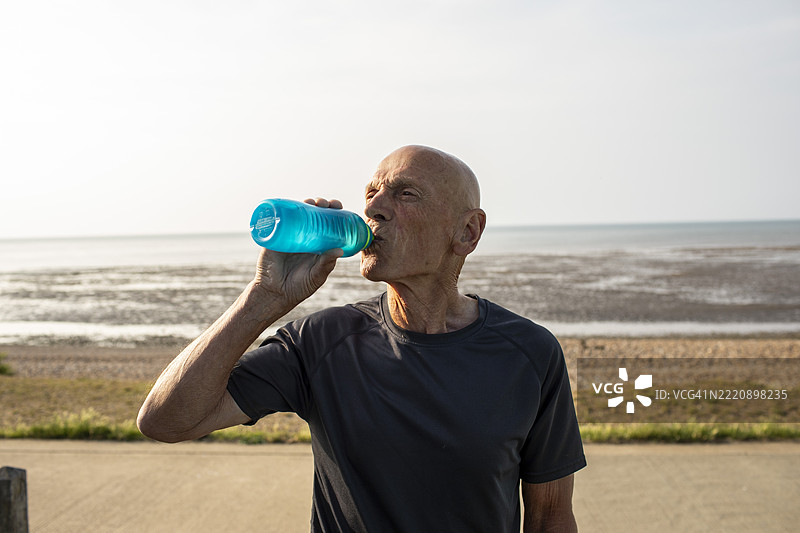 活跃的老年男子在海岸边喝水图片素材
