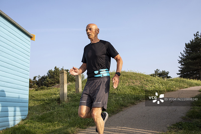 活跃的老年男子在海滩小屋旁跑下坡道图片素材