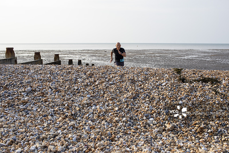活力四射的老年男子在卵石海滩上奔跑图片素材