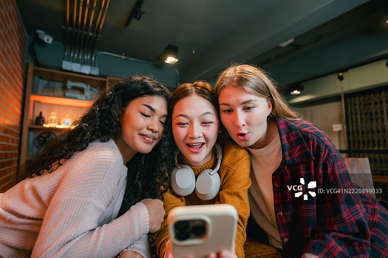 一群朋友围坐在智能手机旁，使用人工智能应用程序来帮助他们的团队项目。图片素材