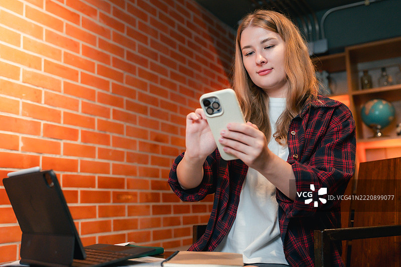 大学生专注于她的智能手机，使用现代人工智能应用程序来帮助学习的特写镜头图片素材