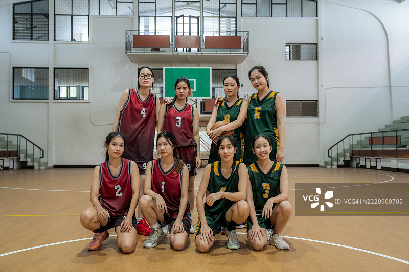 在体育馆里微笑的快乐年轻女性篮球运动员的肖像图片素材