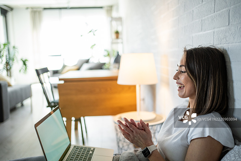 年轻女性在家中视频会议时拍手微笑图片素材