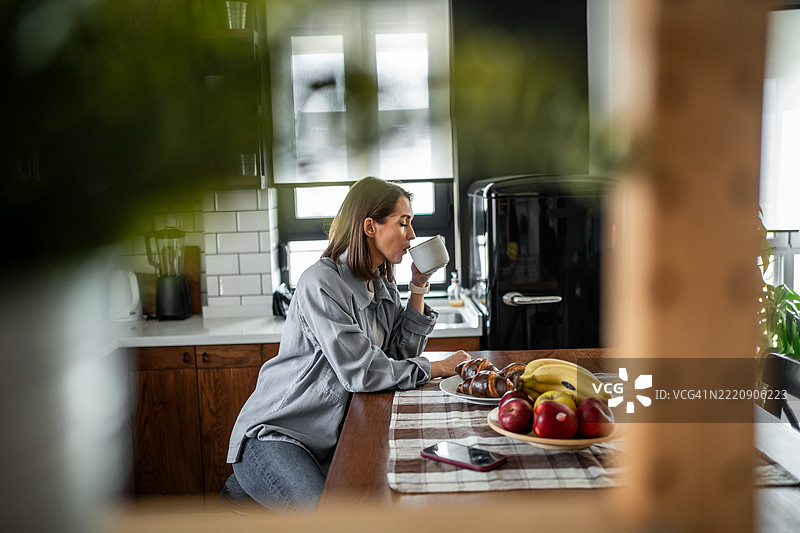 年轻女性在厨房享受轻松的早晨咖啡图片素材