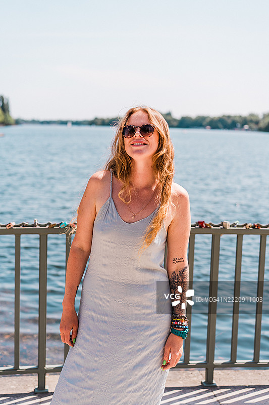 女人在宁静的水边享受阳光明媚的户外时光图片素材