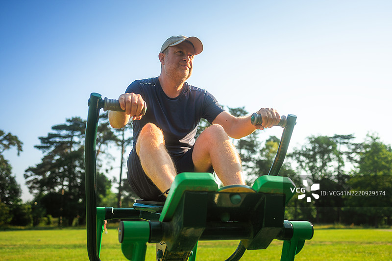 中年男子在户外健身房使用划船机图片素材