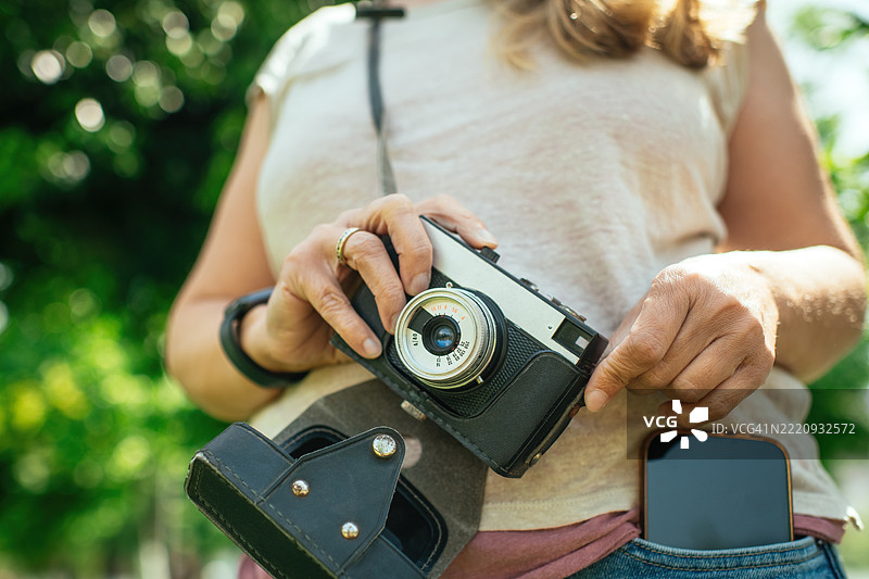 夏天户外拿着胶卷相机和智能手机的女性图片素材