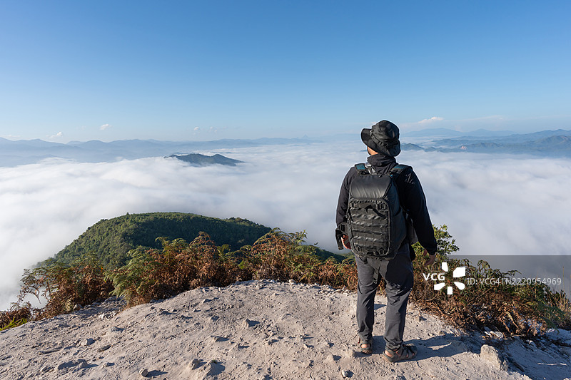 一名男子站在山顶，晨曦中俯瞰云海。图片素材