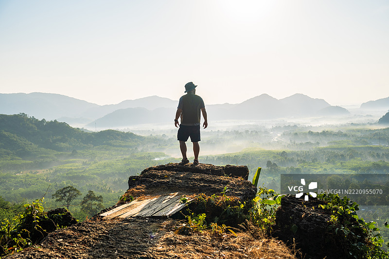 一名男子站在泰国法塔隆的山顶，背景是美丽的风景。图片素材