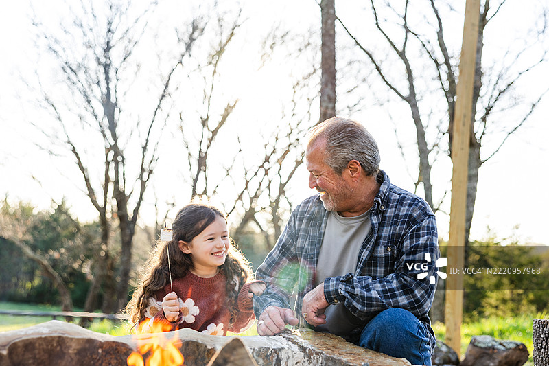 祖父和孙女在篝火旁烤棉花糖图片素材