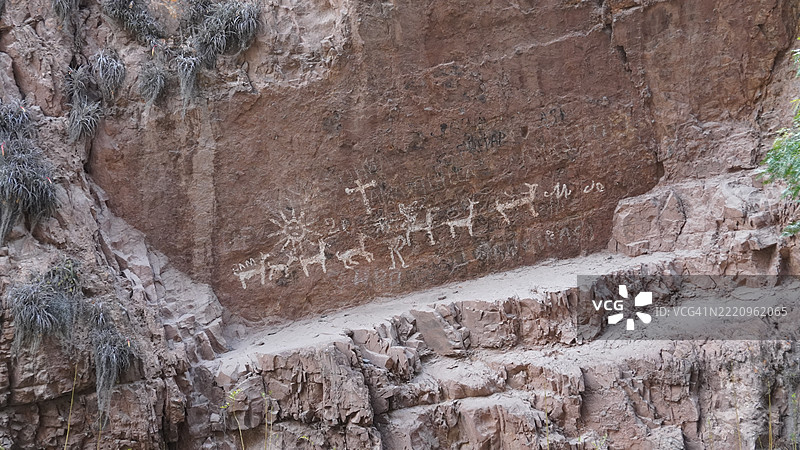 岩石上的洞穴画，描绘了与秘鲁文化相关的美洲驼、太阳和人们。图片素材