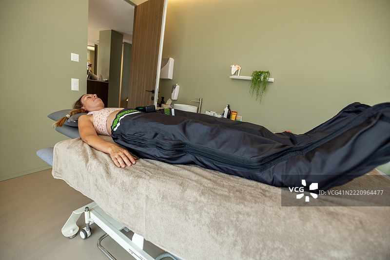 女性客户正在接受空气压缩腿部袖套的淋巴引流治疗图片素材