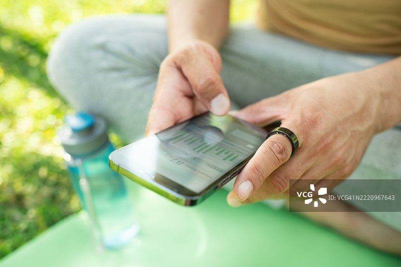 戴着智能戒指的男子在户外练习瑜伽时查看智能手机图片素材