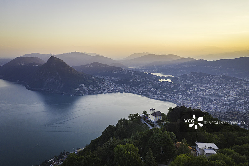 日落时分的卢加诺湖和卢加诺市的鸟瞰图图片素材