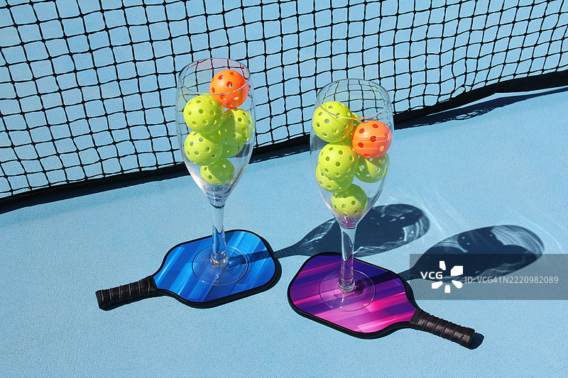 两个超大酒杯与彩色乒乓球拍上的泡菜球在户外展示图片素材