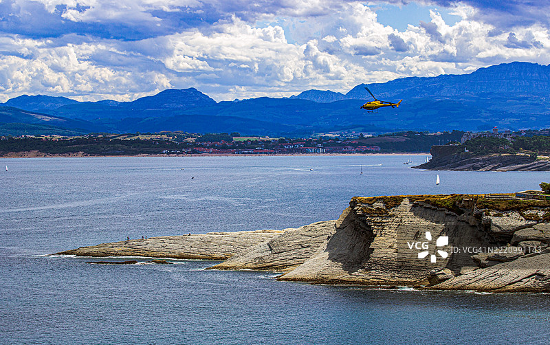 黄色直升机飞越坎塔布里亚海岸图片素材