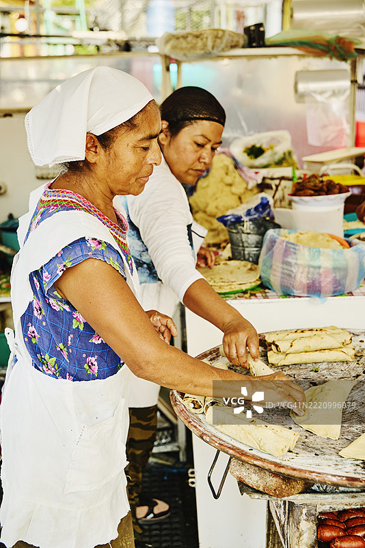 中景拍摄的女性在市场摊位上烹饪传统墨西哥美食图片素材