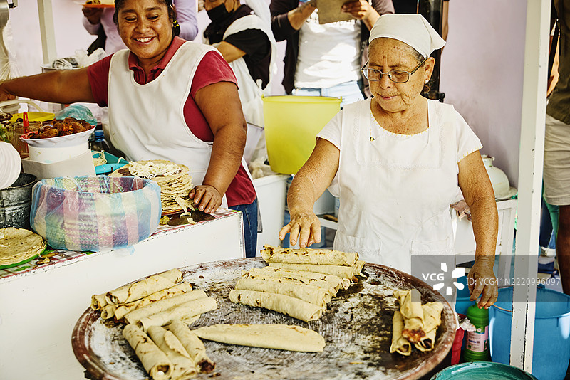 中景拍摄女性在摊位上制作传统瓦哈卡法拉塔。图片素材
