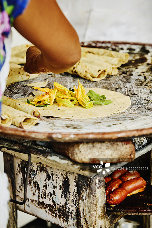 中近景女性手在烤架上制作南瓜花玉米饼图片素材