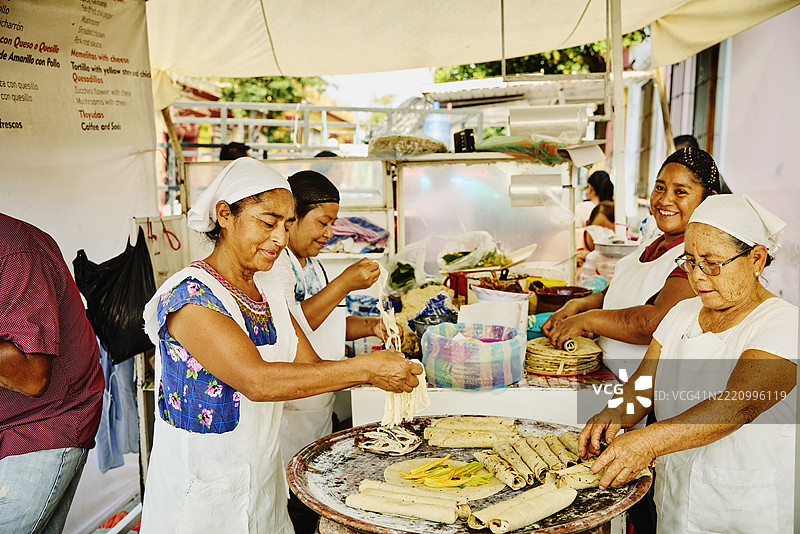 户外摊位的女性厨师正在制作法拉塔和玉米饼。图片素材