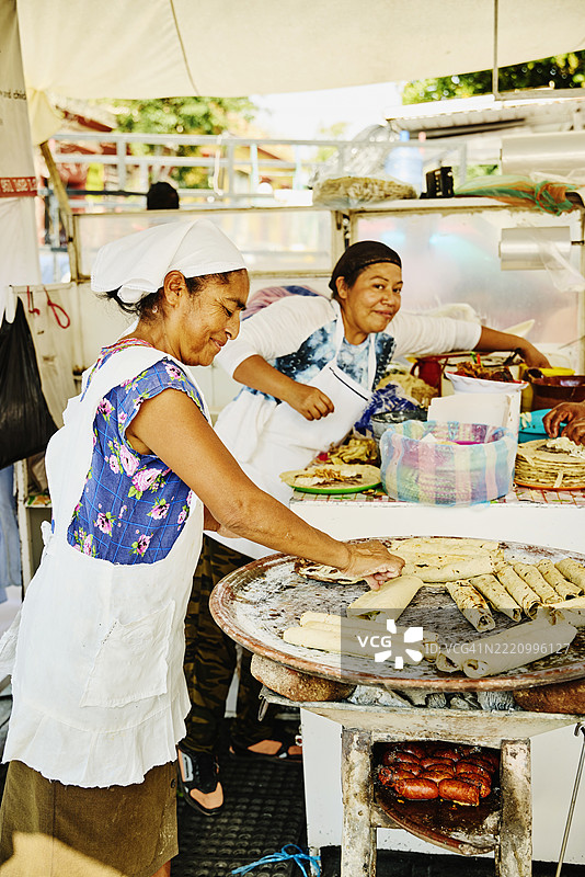 宽镜头拍摄女性在瓦哈卡街头制作法拉塔和玉米饼。图片素材