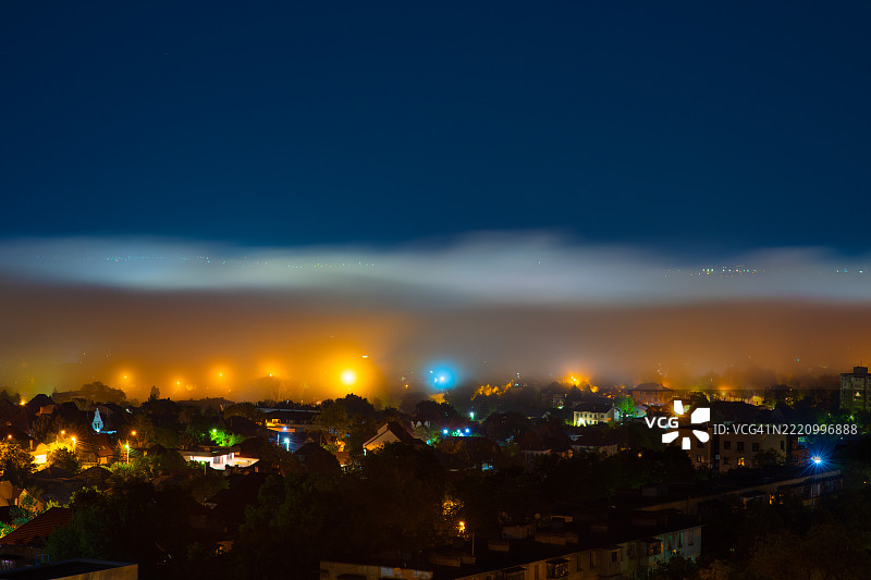 夜晚灯光璀璨的城市天际线，雾蒙蒙的地平线下是晴朗的夜空图片素材