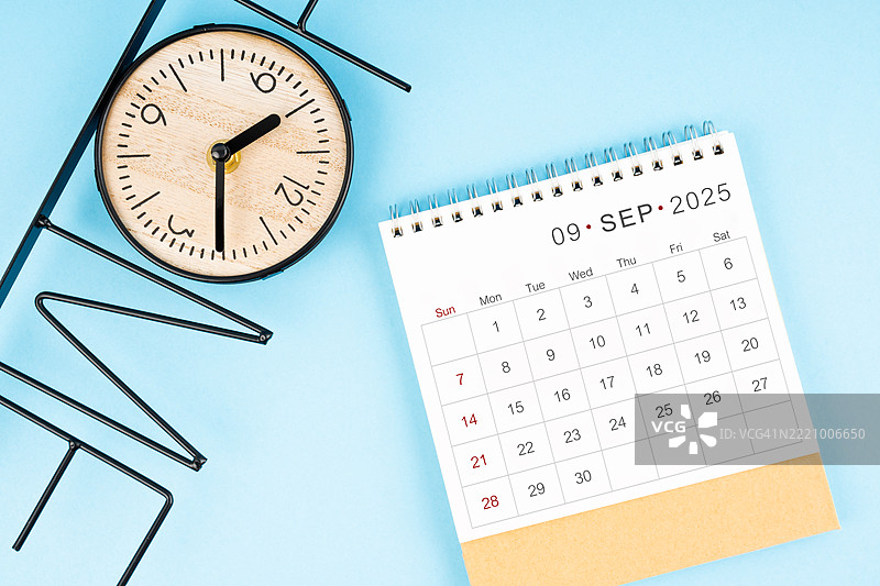 2025年九月桌面日历，蓝色背景上的时钟，平铺展示。图片素材