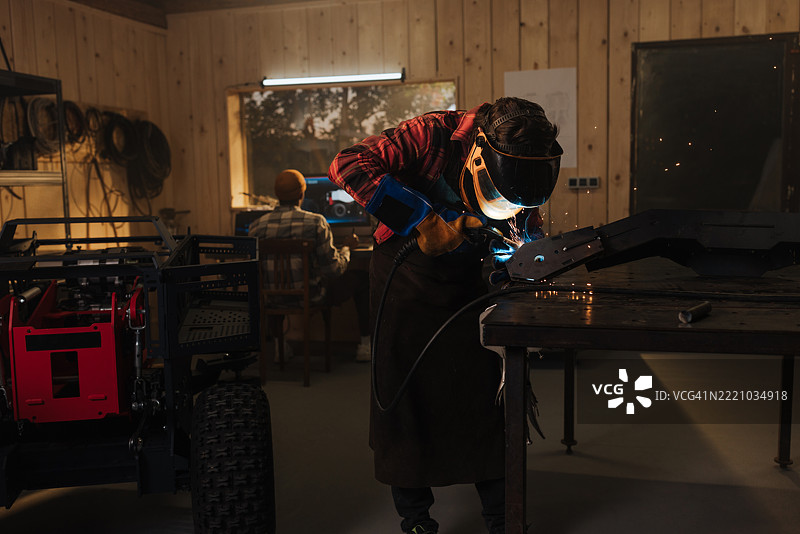 工程师们在车间焊接金属部件，正在制作机器人原型。图片素材