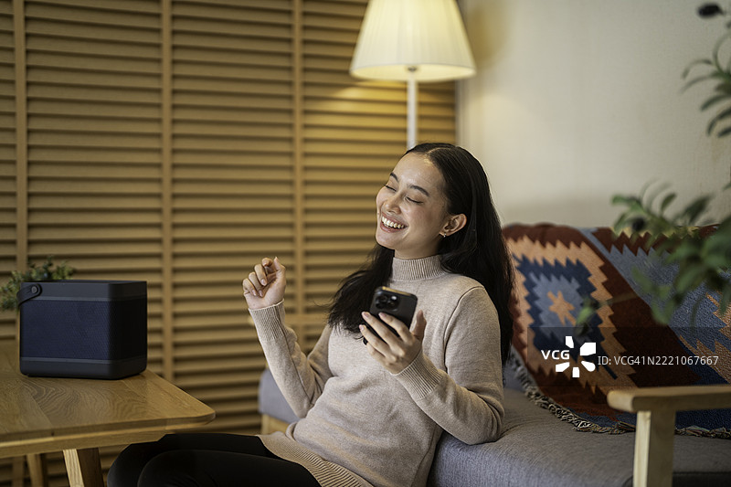 年轻女性在家中通过蓝牙音箱听音乐图片素材