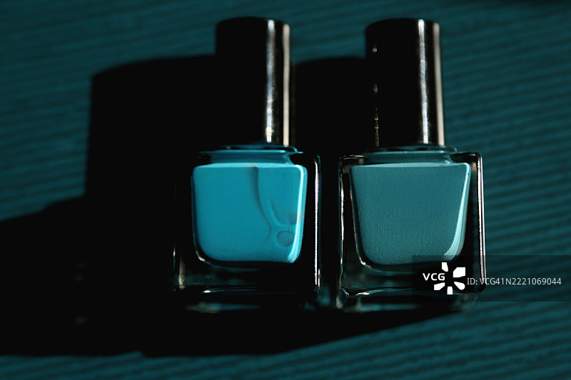 两瓶蓝色指甲油与鲜艳的陶瓷背景相映衬图片素材