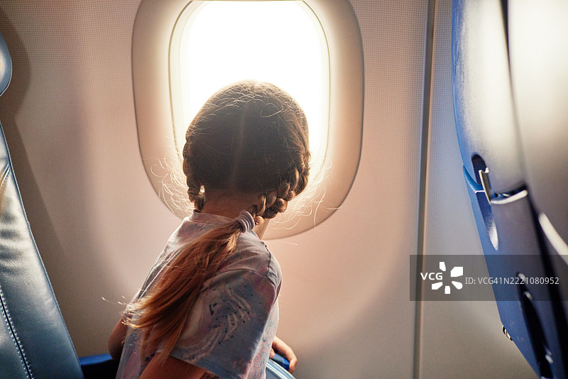 小女孩在飞行中欣赏飞机窗外的景色图片素材