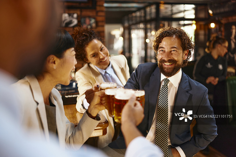 快乐的商人在酒吧与同事们举杯庆祝欢乐时光。图片素材