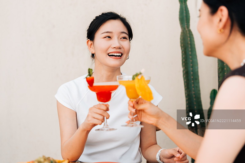 亚洲女孩与朋友一起喝橙汁的肖像。图片素材