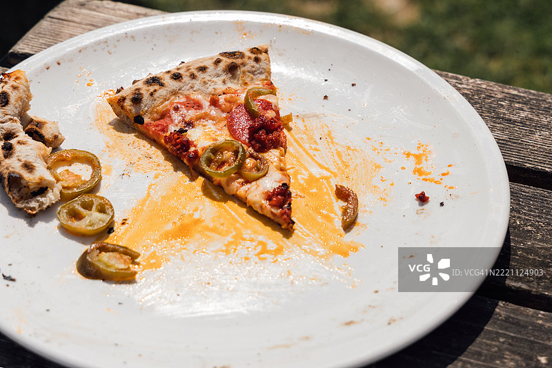 户外用餐后，凌乱盘子上的最后一片披萨图片素材