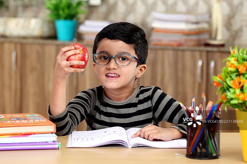 放松的小学生手里拿着红苹果图片素材