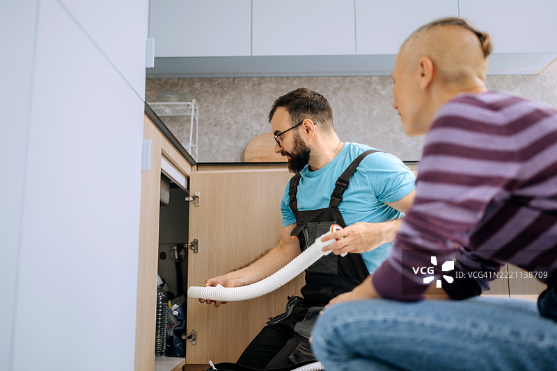 修理工在公寓里为女性修理厨房水槽图片素材
