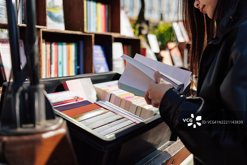 顾客在户外书市摊位浏览书籍图片素材