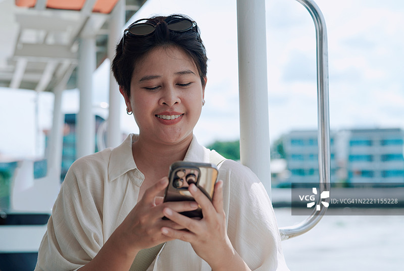 年轻女性在游船上使用手机图片素材