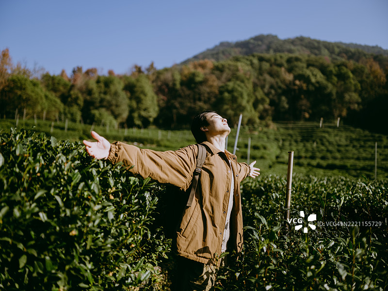 一位年轻的亚洲男子站在山谷中享受新鲜空气图片素材