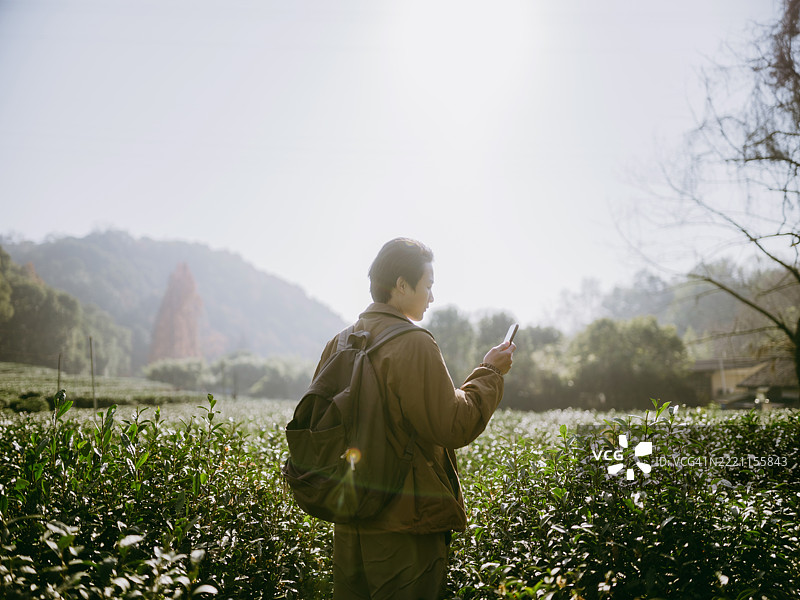 一位年轻的亚洲男子站在山谷中使用智能手机图片素材