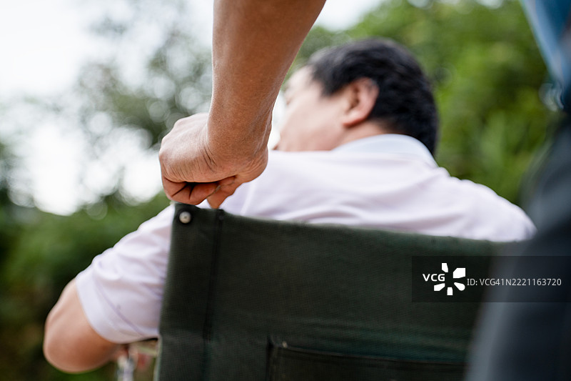 中老年人正在推着一位腿部失去行走能力的老年残疾人。图片素材